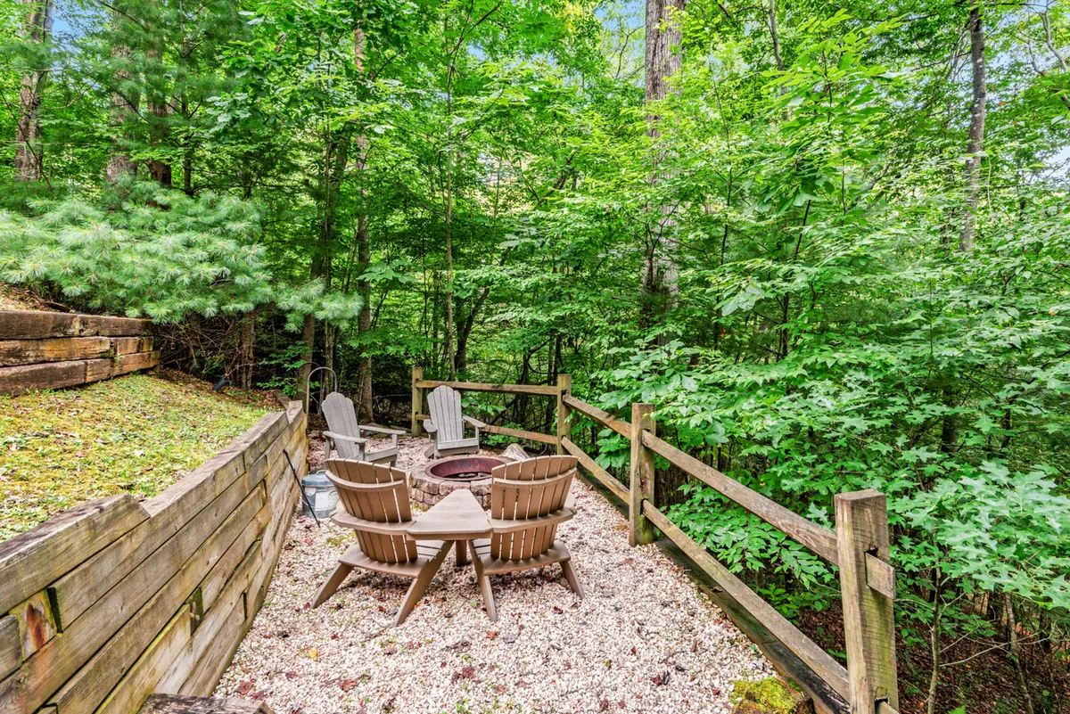 An inviting outdoor fire pit with wooden seating nestled among the trees. The setup is perfect for gathering under the stars, telling stories, or simply relaxing in the quiet of the woods.