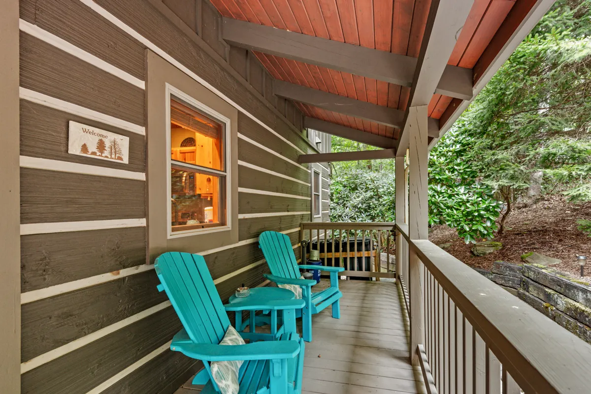 A deck with Adirondack chairs, a welcome sign, wooden railing, and lush greenery. The area is inviting, perfect for evening relaxation, stargazing, or casual conversation after a day of adventure. The welcoming ambiance supports the idea of gathering and sharing stories under the stars.